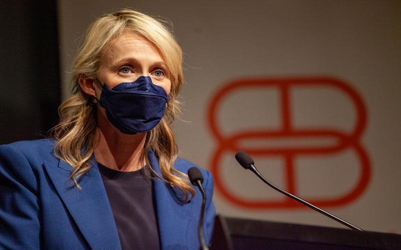Bronwyn King speaking on a podium wearing a mask and blazer.