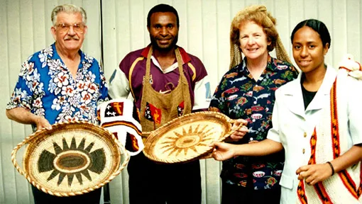 Margery Nash, her husband Ken, and colleagues holding woven trays and bags.