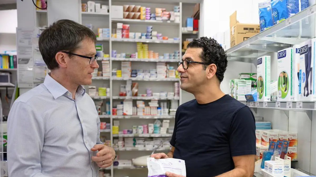 Pharmacist Ali Mafi talks to Professor Joe Doyle in a pharmacy.
