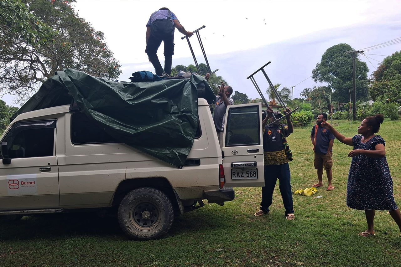 Burnet staff and community researchers unload screening equipment from a station wagon car.