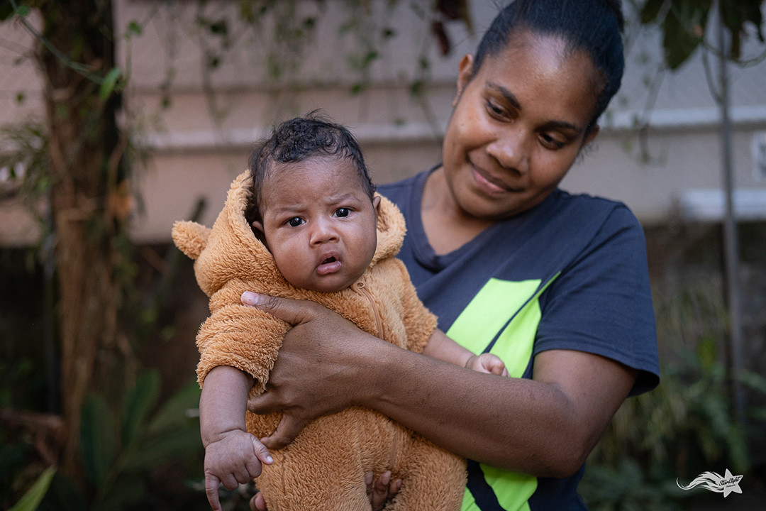 Mother in Vanuatu holds a baby facing the camera.