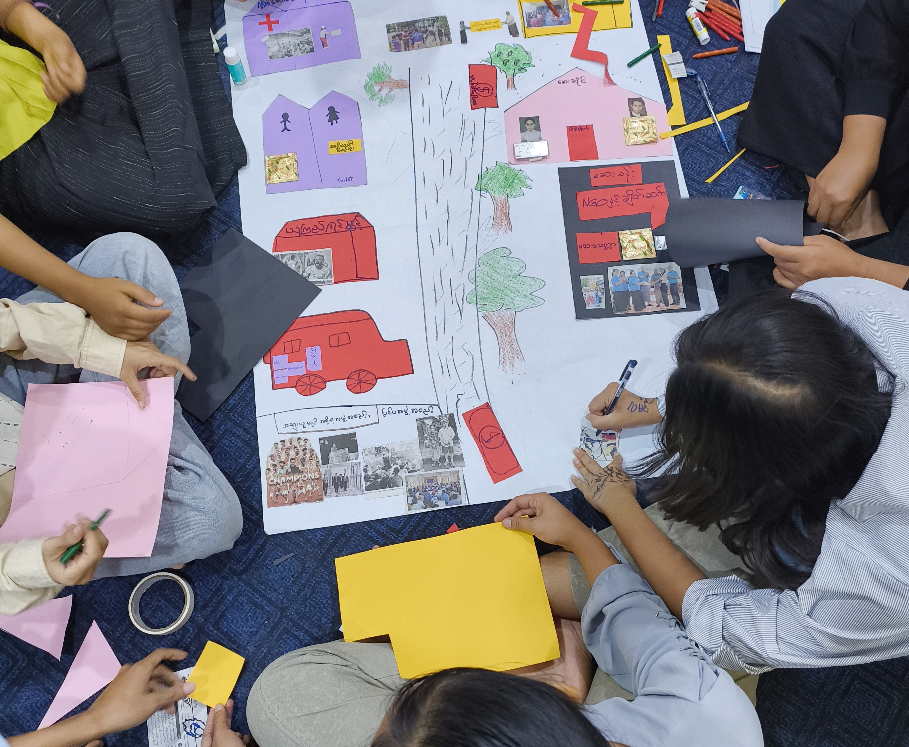 Young people creating a collaborative artwork showing a city and safe community spaces.
