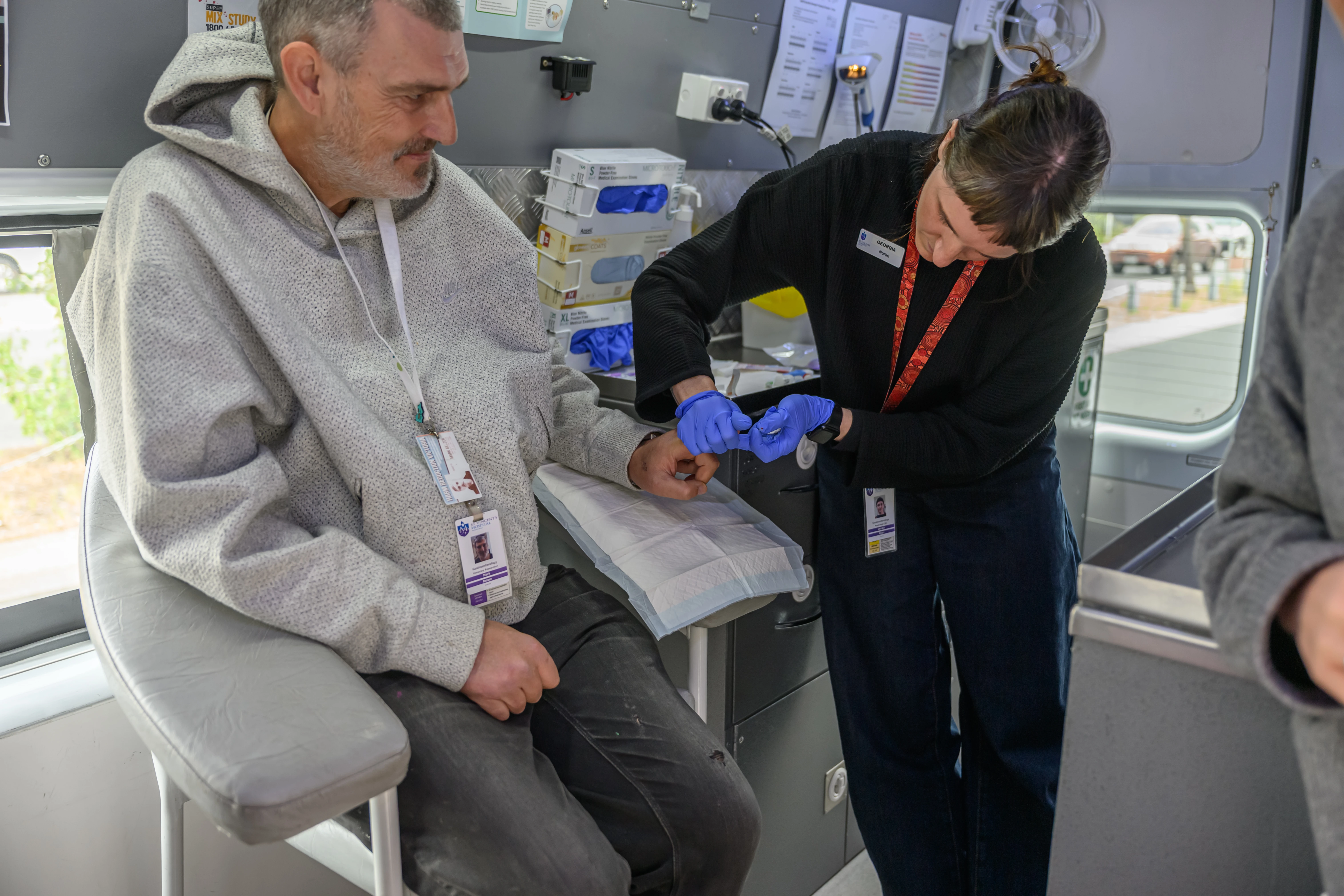 Nurse Georgia demonstrates finger prick testing with Mark Belzer in the C no more mobile hepatitis C testing van.