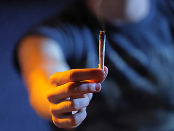 Close up on hand holding a smoking joint.