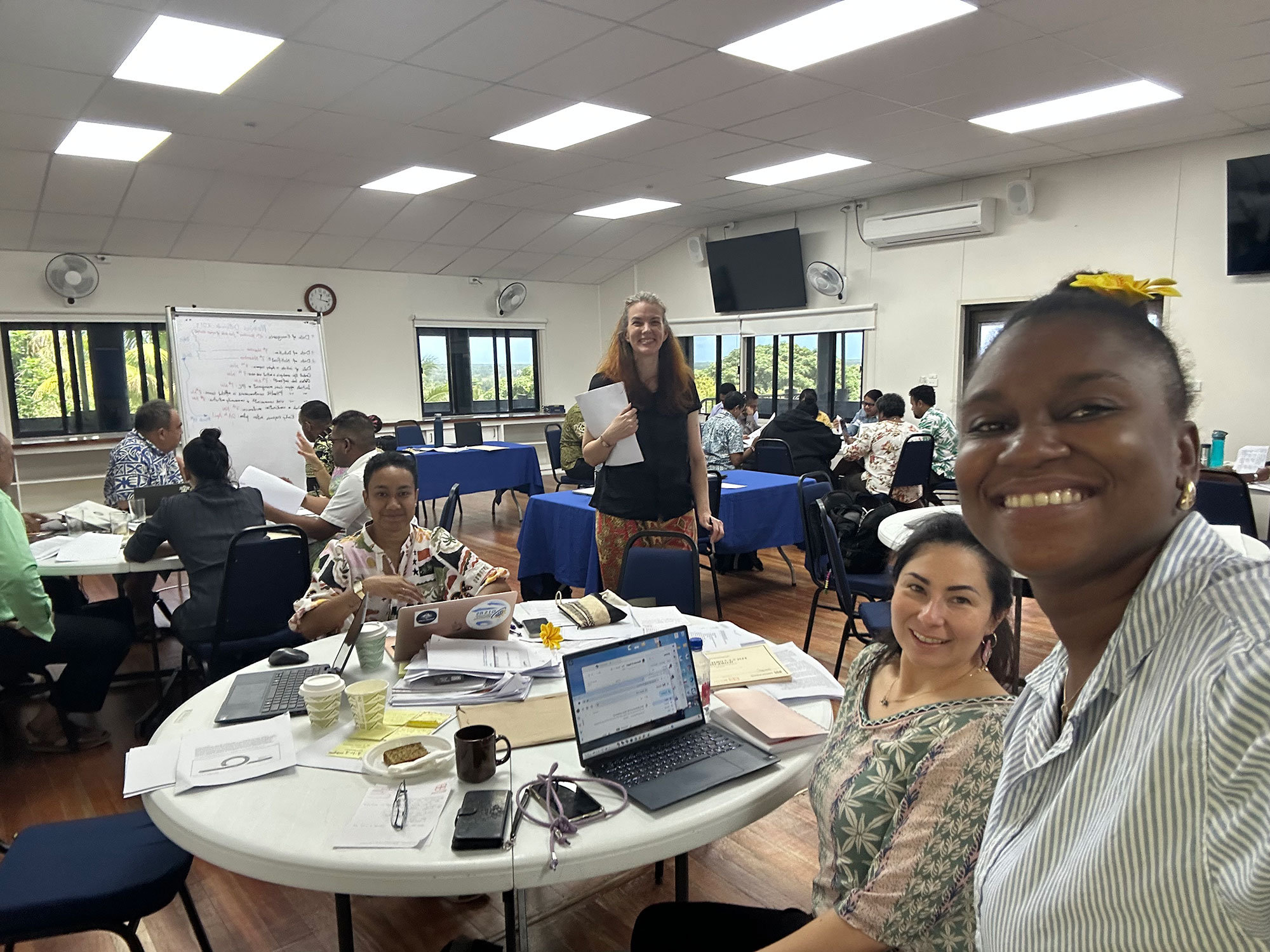 Four people pose for a selfie in a conference room. They are attending a 7-1-7 workshop