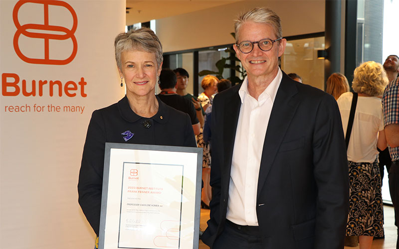 Caroline Homer (left) holding a framed award, with Professor Brendan Crabb (right).