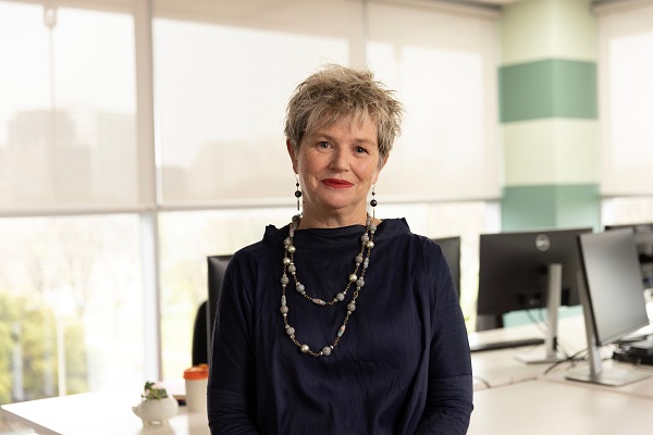 Woman with short hair in an office setting, smiling at the camera.