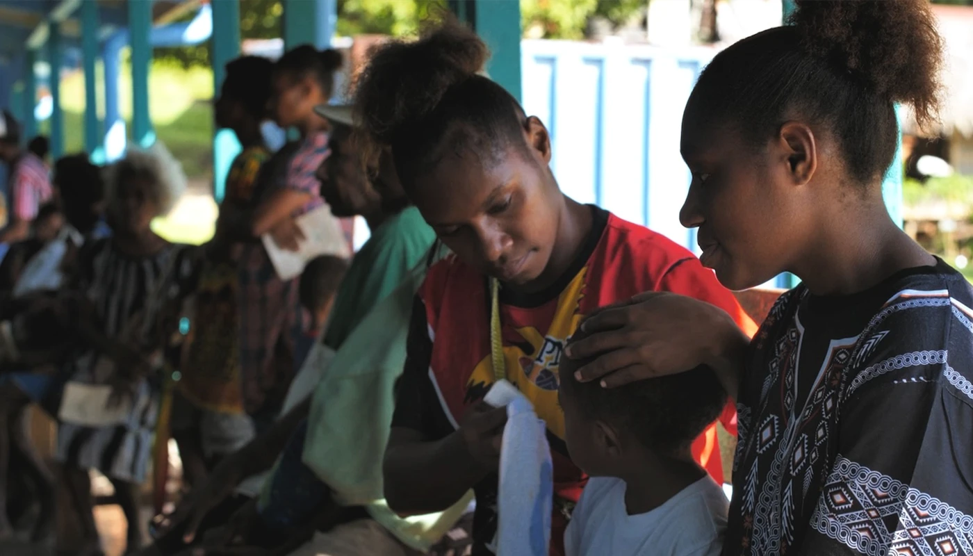 Women, men and children sitting outside together.