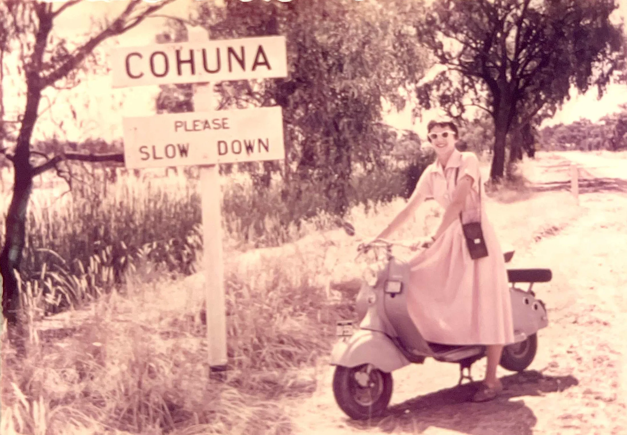 Heather Phiddian on a moped in front of a sign that reads Cohuna.