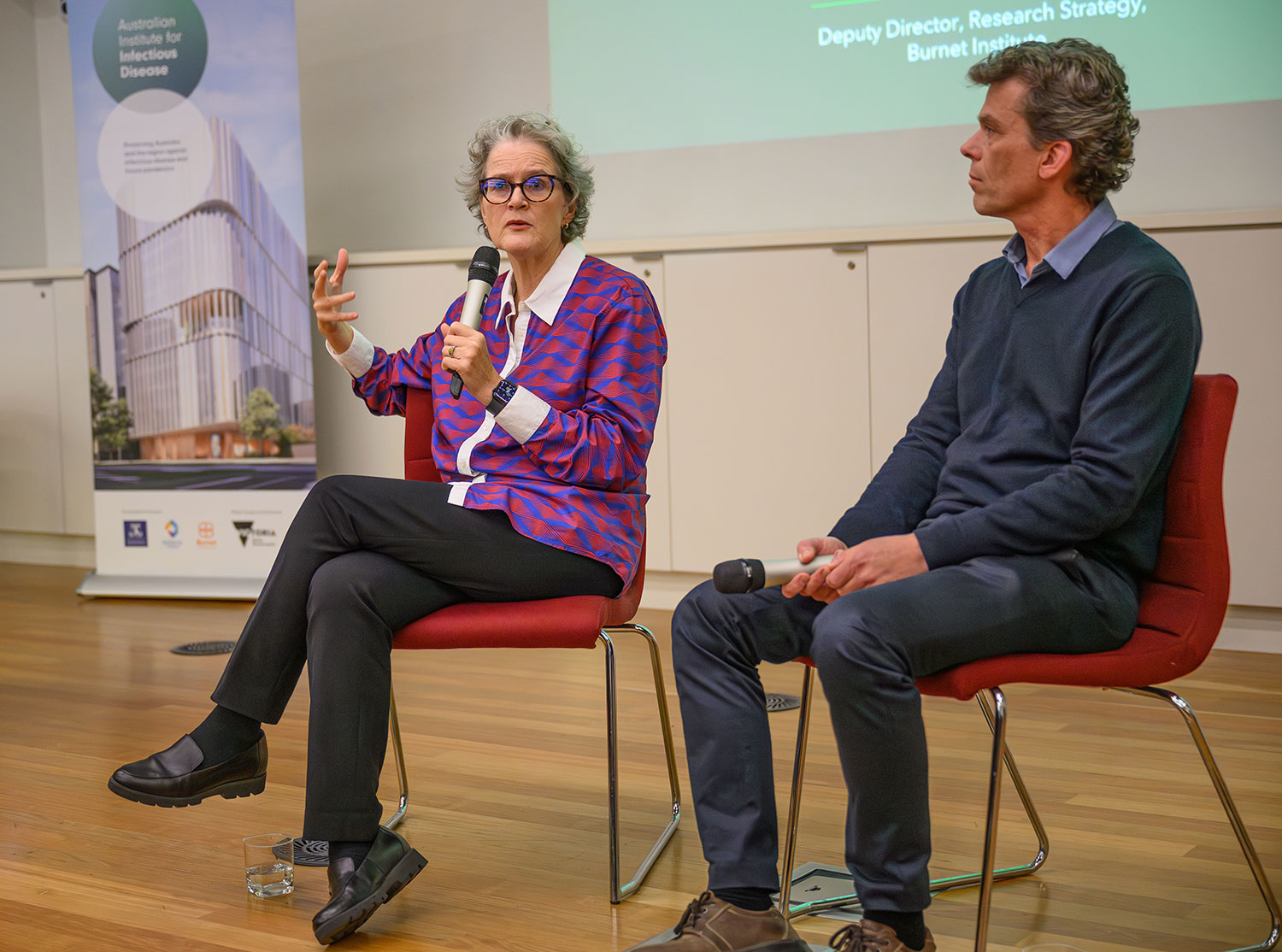 Dr Jeanne Marrazzo and Professor James Beeson sit on chairs. Dr Jeanne is talking into a microphone.