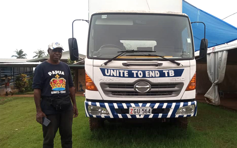 Yanga Koiti standing next to the SWEEP TB van which reads 'Unite to end TB'