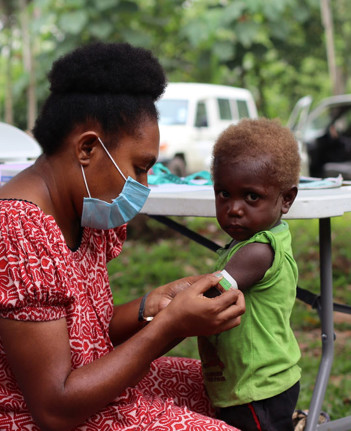 A parent or caregiver tending to a child's arm in Papua New Guinea.